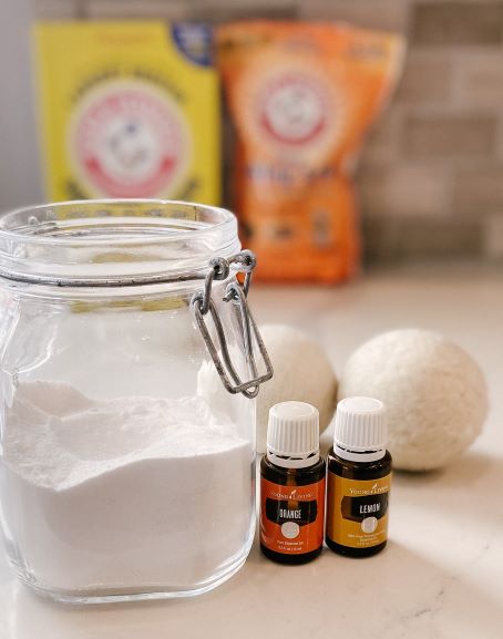 homemade laundry scent booster in a glass jar essential oils washing soda baking soda on counter