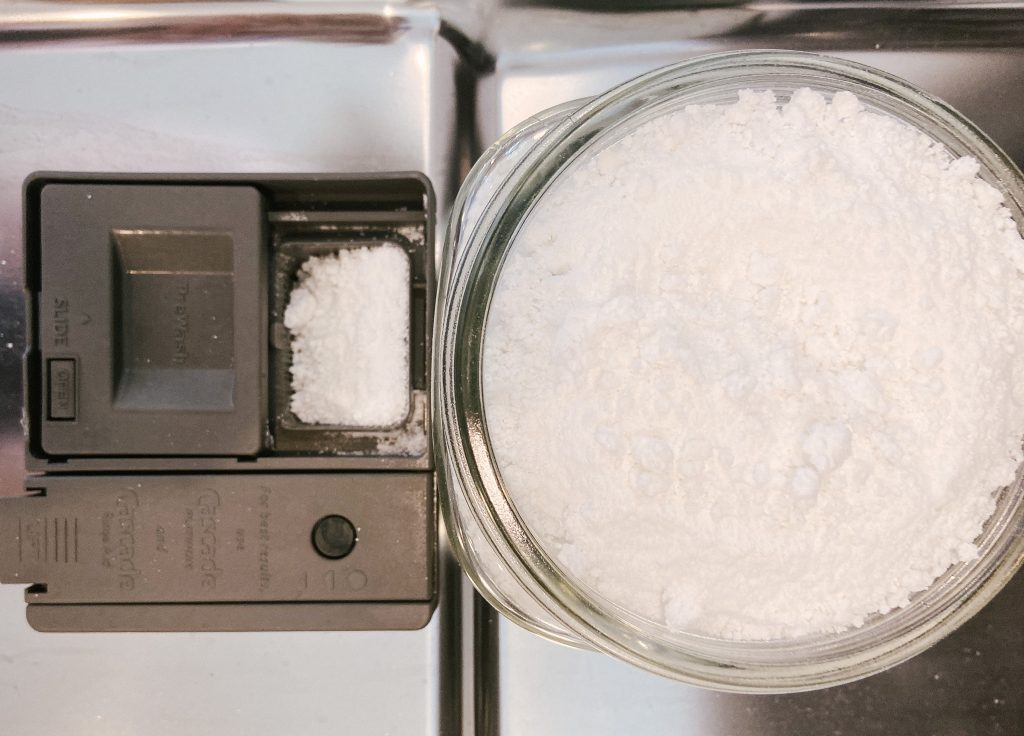 glass jar with dishwasher powder and  dishwasher powder in dishwasher 